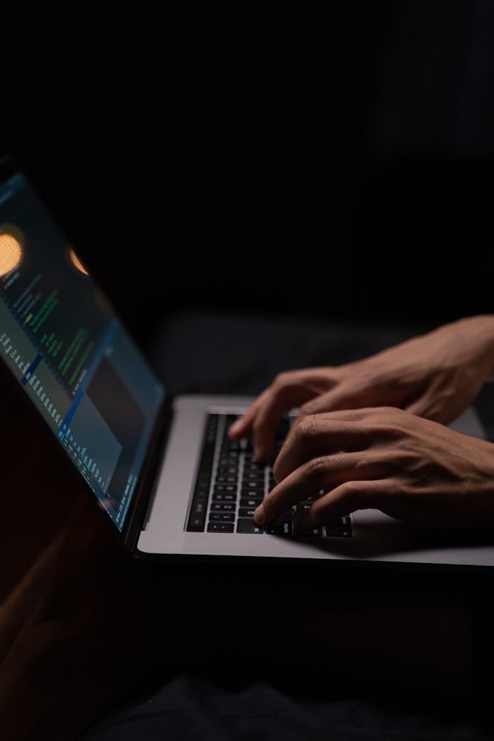 creative-02 Hands typing code on a laptop keyboard in a dark room, capturing the essence of late-night programming.